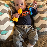 Isaac is registered to the contest to win money with this photo: baby, chicago_bears, child, clothing, cushion, cute, eyes, face, giraffe_toy, hand, indoor, infant, pants, patterned_cushion, person, plastic_keys, portrait, relaxed, socks, toy