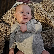 Elon participe au concours pour gagner de l'argent avec cette photo : baby, child, infant, smiling, onesie, blanket, fluffy, cozy, indoor, person, happy, cute, face, skin, head, hand, legs, clothing, light, shadow