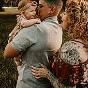 Riya joined the competition — help win amazing prizes! affection, baby, casual, clothing, curly_hair, embrace, family, grass, happy, headband, holding, love, nature, outdoor, person, portrait, smile, tattoo, togetherness, warm_lighting