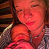 Preston is registered to the contest to win money with this photo: baby, newborn, person, face, holding, sleeping, closeup, striped_clothing, beaded_necklace, nose_ring, red_lighting, indoor, portrait, skin, hand, tender, warm_light, expression, rest, comfort