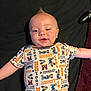 baby, infant, mickey_mouse, onesie, clothing, lying_down, happy, child, face, head, expression, mohawk, arm, black_background, toy_controller, fabric, smile, skin, person, cute