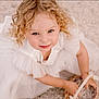 child, girl, curly_hair, blonde, white_dress, basket, smile, face, portrait, looking_up, cute, innocent, young, childhood, happy, sitting, hands, outdoor, soft_lighting, close_up