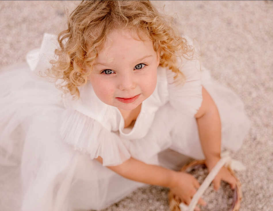 Noami a rejoint le concours — aidez-le/la à gagner de superbes lots ! child, girl, curly_hair, blonde, white_dress, basket, smile, face, portrait, looking_up, cute, innocent, young, childhood, happy, sitting, hands, outdoor, soft_lighting, close_up