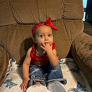 Jo Eva is registered to the contest to win money with this photo: toddler, child, red_headband, red_top, blue_jeans, white_shoes, blanket, stitch_character, armchair, indoor, person, furniture, curious, sitting, baby, cute, clothing, home, expression, hand