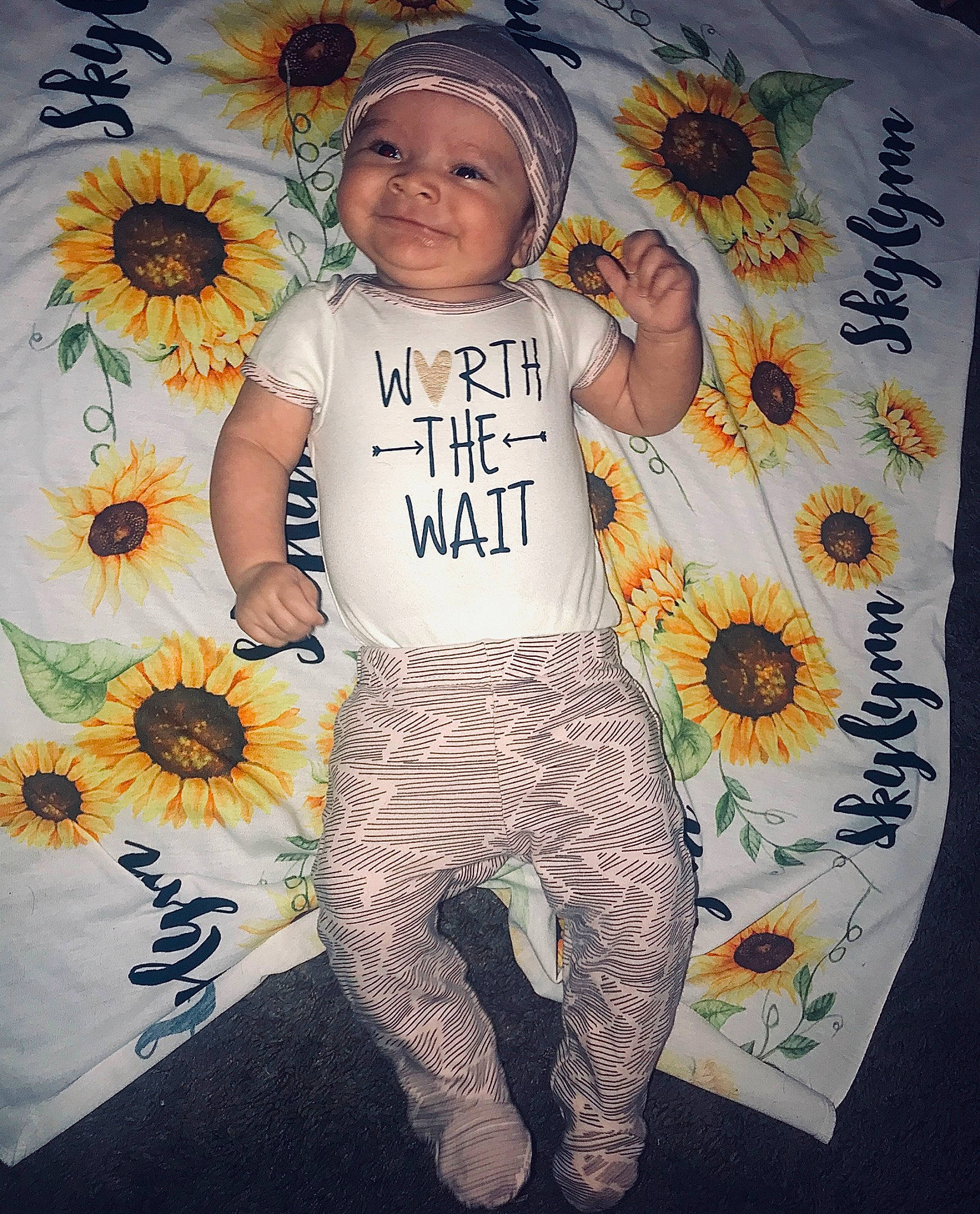 Skylynn is registered to the contest to win money with this photo: baby_toddler_clothing, child, clothing, headwear, joy, pattern, person, plant, sleeve, sunflower, t_shirt, toddler, top