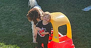 Aryatanner joined the competition — help win amazing prizes! child, toddler, smiling, outdoor, backyard, grass, dogs, pets, animal, toy_car, ride_on_toy, red, yellow, sunlight, house, garden, portrait, standing, boots, playtime
