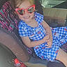 child, toddler, smiling, heart_shaped_sunglasses, blue_dress, hello_kitty, car, car_seat, seatbelt, passenger, portrait, indoor, vehicle, cardboard_box, water_bottle, fashion, happy, patterned_clothing, sitting, family_trip