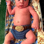James joined the competition — help win amazing prizes! baby, infant, blanket, knitted, crochet, diaper_cover, blue, brown, skin, face, eyes, hand, fist, legs, bare_chest, newborn, cute, lying_down, cozy, indoor