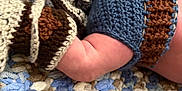 James joined the competition — help win amazing prizes! baby, arm, knitted_clothing, blue, brown, blanket, textured, soft, crochet, fabric, closeup, infant, skin, handmade, warm, resting, cozy, colorful, pattern, child