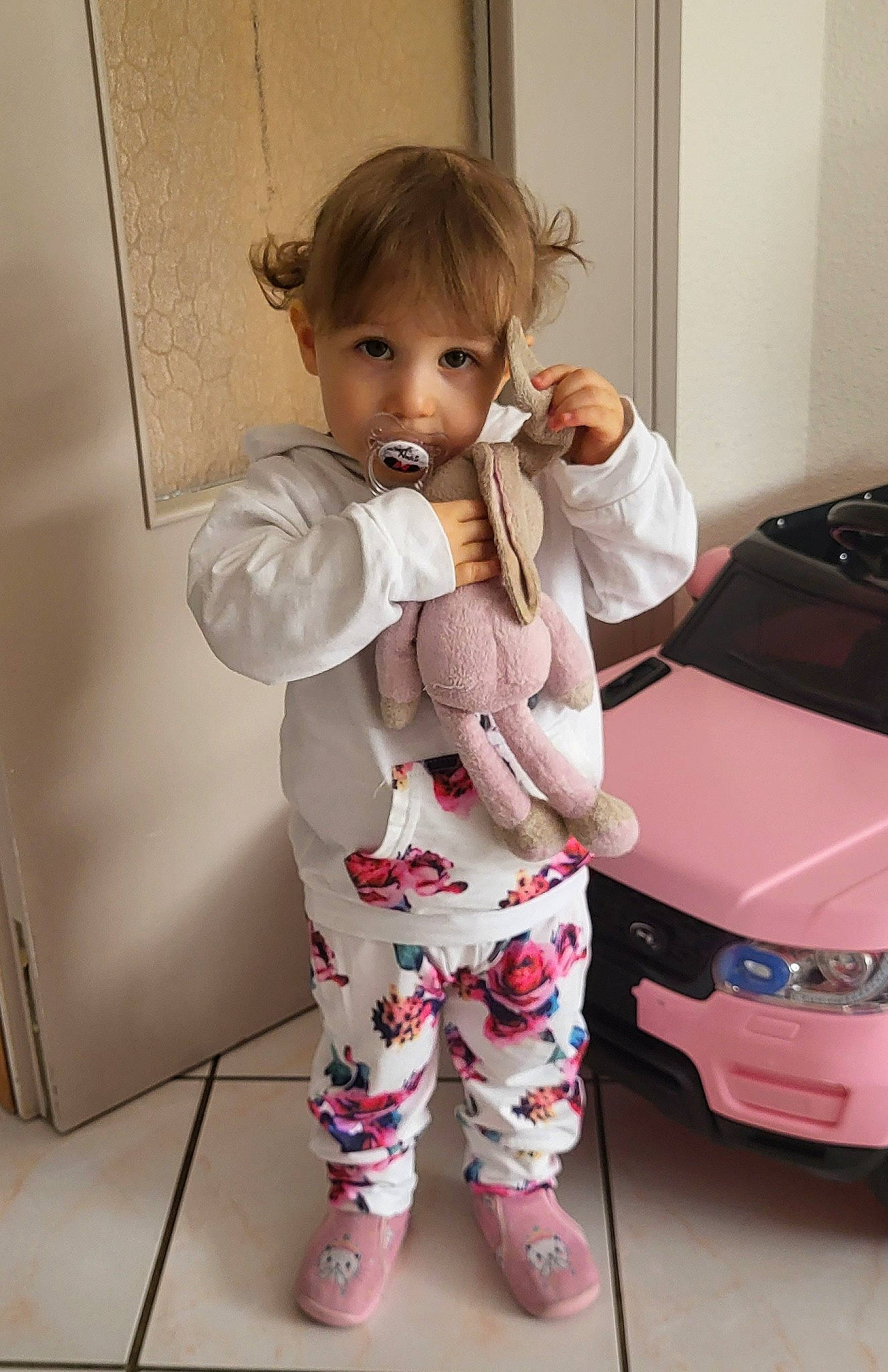 Amélia participe au concours pour gagner de l'argent avec cette photo : automotive_design, automotive_exterior, baby, baby_toddler_clothing, child, clothing, dress, face, floor, flooring, hood, joint, person, personal_luxury_car, pink, shoe, skin, sleeve, stuffed_toy, toddler
