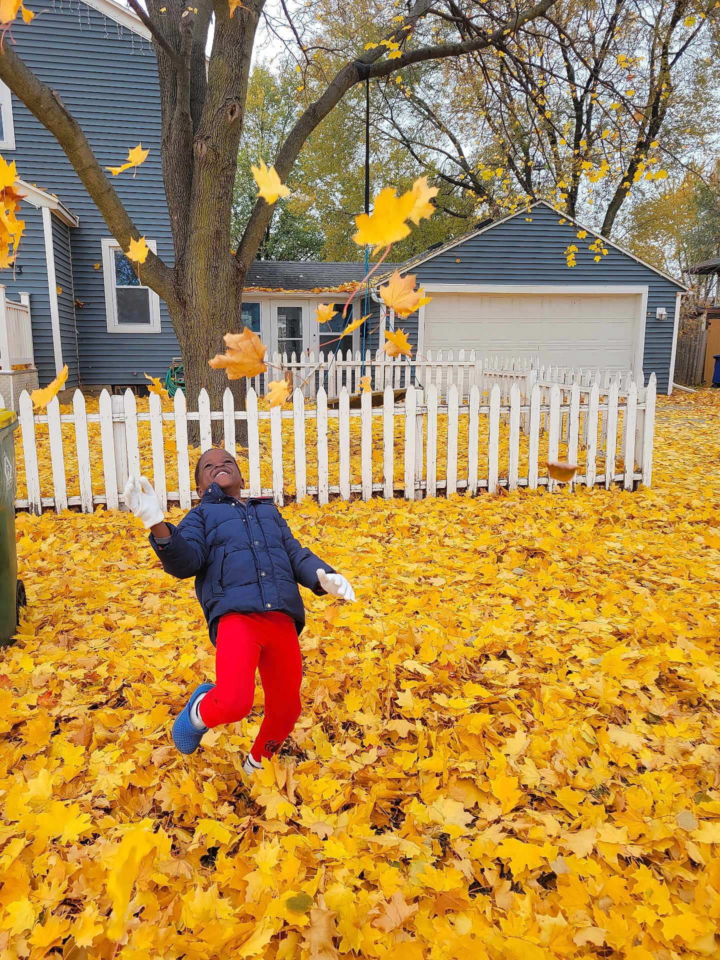 Alexander joined the competition — help win amazing prizes! child, autumn, fall_leaves, yellow_leaves, playing, outdoor, jacket, red_pants, white_gloves, smiling, tree, fence, house, backyard, seasonal, happy, leaves_in_air, nature, yard, casual_clothing