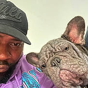 Pluto joined the competition — help win amazing prizes! man, dog, french_bulldog, cap, hoodie, purple_clothing, pet, selfie, indoor, closeup, wrinkles, face, portrait, expression, companion, animal, casual, beard, headwear, friendship