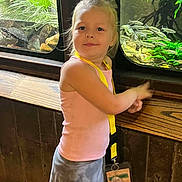 Athena joined the competition — help win amazing prizes! child, toddler, girl, blonde_hair, smiling, portrait, aquarium, fish, aquatic_plants, indoor, zoo, standing, pink_shirt, gray_shorts, yellow_straps, wooden_paneling, nature, wildlife, happy, photography
