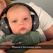 Phoenix joined the competition — help win amazing prizes! baby, infant, child, face, portrait, headphones, earmuffs, hockey_game, sports_arena, spectator, green_shirt, adult, parent, indoor, seating, close_up, wide_eyed, calm, text_overlay, selfie