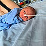 newborn, baby, infant, blue_clothing, feeding_tube, hospital, blanket, arm, person, lying_down, face, healthcare, medical_equipment, bed, skin, young_child, closeup, indoors, comfort, resting
