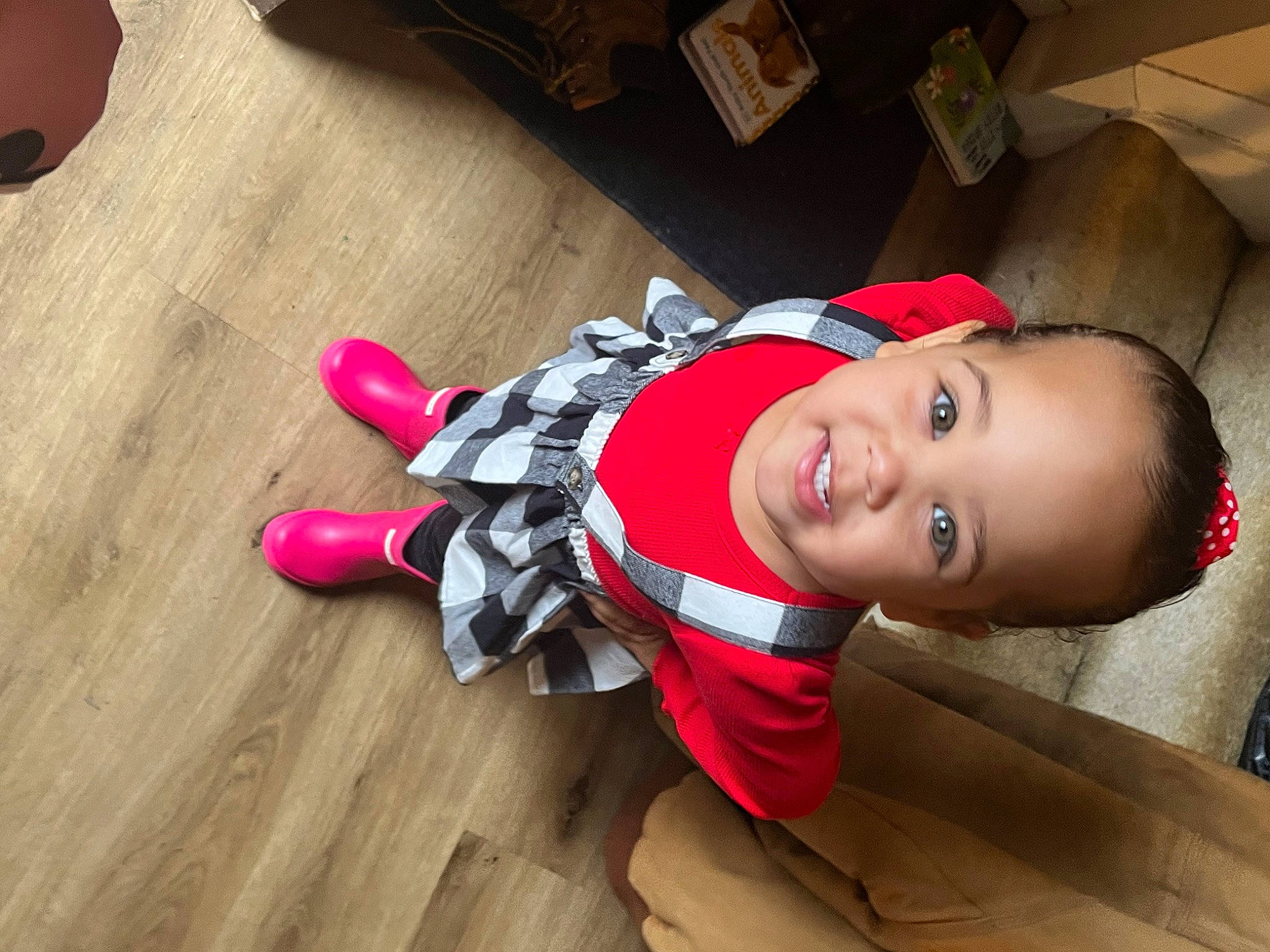 Reagan is registered to the contest to win money with this photo: automotive_wheel_system, baby, baby_toddler_clothing, carmine, child, fashion_accessory, floor, flooring, fun, happy, hardwood, hat, person, room, sitting, smile, toddler, varnish, wood, wood_flooring