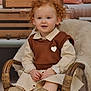 Aliya participe au concours pour gagner de l'argent avec cette photo : child, toddler, curly_hair, red_hair, wicker_chair, boots, brown_vest, heart_emblem, fur_throw, vintage_suitcases, pastel_cushions, indoor, portrait, smiling, seated, cute, comfortable, cozy, furniture, clothing