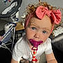 Aliya a rejoint le concours — aidez-le/la à gagner de superbes lots ! toddler, child, pacifier, curly_hair, pink_bow, white_shirt, indoor, baby_gear, stroller, chair, floor, beads, toy, curious, cute, person, home, furniture, portrait, closeup