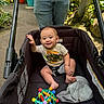 Greyson joined the competition — help win amazing prizes! baby, stroller, child, smiling, toy, hat, outdoor, plants, greenery, person, jeans, tshirt, hand, foot, seat, sunlight, pathway, colorful, nature, casual