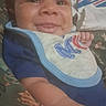 Elijah joined the competition — help win amazing prizes! baby, infant, child, smiling, face, portrait, close_up, lying_down, bib, blue_clothing, bed, blanket, bedding, patterned_fabric, indoors, happy, hand, arm, eyes, photography