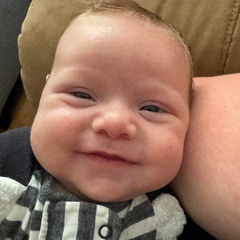 Elijah joined the competition — help win amazing prizes! baby, child, closeup, couch, cozy, cushion, cute, expression, face, happy, head, indoors, infant, person, portrait, resting, skin, smiling, striped_clothing, young