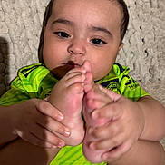 Zohan is registered to the contest to win money with this photo: baby, blanket, child, closeup, cute, expression, face, feet, foot_holding, green_clothing, hands, indoor, infant, jersey, lying_down, manchester_city, person, portrait, skin, texture