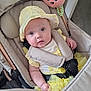 baby, baby_accessories, baby_clothing, blue_eyes, child, curious_expression, fabric, flooring, hand, headwear, indoor, infant, pale_skin, person, plush_toy, seat_belt, soft_toys, stroller, yellow_dress, yellow_hat