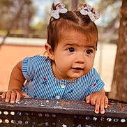 Heïana a rejoint le concours — aidez-le/la à gagner de superbes lots ! baby, bench, blue_dress, child, curious, cute, daylight, expression, face, hair_bows, hands, nature, outdoor, person, playground, portrait, skin, striped_clothing, toddler, young_child