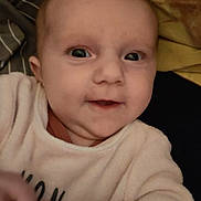 Kathaleya a rejoint le concours — aidez-le/la à gagner de superbes lots ! baby, infant, face, closeup, smile, eyes, hand, clothing, blanket, sleepwear, cute, portrait, child, soft, warm, indoor, expression, skin, head, young