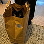 cat, black_cat, paper_bag, curious, yellow_eyes, indoor, carpet, floor, curtain, shadow, peek, pet, animal, whiskers, ears, home, cozy, mystery, container, playful