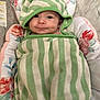 baby, infant, striped_towel, green, white, hood, smile, face, cushion, floral, pattern, blanket, cute, child, wrapped, lying_down, soft, comfortable, indoor, portrait