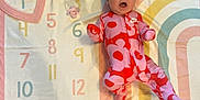 Kehlani joined the competition — help win amazing prizes! baby, infant, onesie, headband, bow, milestone_blanket, numbers, colorful, pink, red, lying_down, cute, child, apparel, patterned_clothing, expression, indoors, soft_texture, pastel_colors, playtime