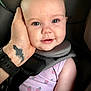 Aubrey joined the competition — help win amazing prizes! baby, child, face, blue_eyes, smile, hand, tattoo, car_seat, seatbelt, clothing, pink, floral_pattern, infant, closeup, skin, person, cute, portrait, safety, happy