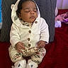 Ameera is registered to the contest to win money with this photo: baby, sleeping, hooded_sweater, white_clothing, floral_pants, knitted_booties, pillow, red_blanket, indoor, infant, cute, peaceful, child, portrait, soft_lighting, cozy, resting, small_hands, seated, warm_clothing