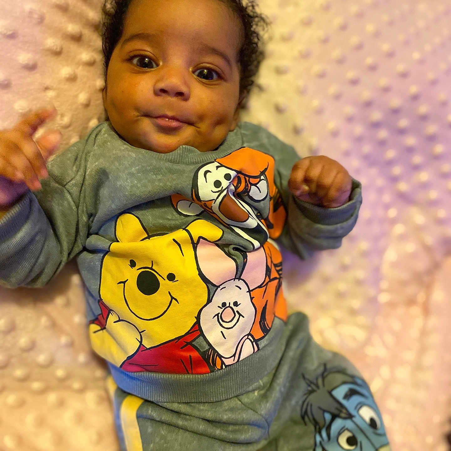 Ameera is registered to the contest to win money with this photo: baby, infant, child, cute, dimples, winnie_the_pooh, tigger, piglet, eeyore, clothing, sweatshirt, pants, soft_blanket, pink, texture, lying_down, portrait, smiling, indoors, person