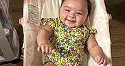 Anahi joined the competition — help win amazing prizes! arm, baby, baby_bouncer, child, comfort, cute, face, floral_pattern, furniture, happy, indoor, infant, leg, onesie, person, relaxation, seat, skin, smiling, wooden_floor