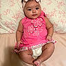 Anahi is registered to the contest to win money with this photo: baby, child, infant, pink_dress, headband, bow, floral_pattern, pillow, bed, cute, chubby, sitting, indoors, portrait, smiling, skin, face, hand, foot, person
