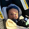 Sylas joined the competition — help win amazing prizes! baby, infant, child, car_seat, vehicle, safety_harness, beanie, blanket, bundled_up, portrait, face, eyes, sunlight, indoor, travel, passenger, cozy, seated, automotive, warning_label