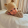 baby, infant, child, portrait, face, eyes, lying_down, bed, blanket, knitwear, hat, bear_hat, clothing, indoors, curtains, soft_lighting, warm_tones, cozy, cute, photography