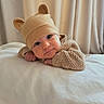 baby, infant, child, portrait, smiling, lying_down, bed, blanket, knitwear, hat, bear_hat, clothing, face, eyes, indoors, bedroom, curtains, soft_lighting, cozy, cute