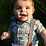 baby, boy, smiling, sitting, grass, outdoor, shirt, suspenders, shorts, face, child, happy, portrait, skin, eyes, hands, wooden_sign, milestone, nature, sunlight