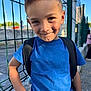 Noah participe au concours pour gagner de l'argent avec cette photo : child, boy, smile, blue_tshirt, backpack, outdoor, fence, sunlight, daylight, person, short_hair, casual_clothing, cheeky, confident, young, portrait, urban, sidewalk, happy, playful
