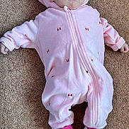 Thea is registered to the contest to win money with this photo: baby, carpet, casual, child, cute, face, footwear, hooded_clothing, indoors, infant, laying_down, minnie_mouse, newborn, person, pink_onesie, portrait, small_baby, socks, soft_clothing, white_shoes