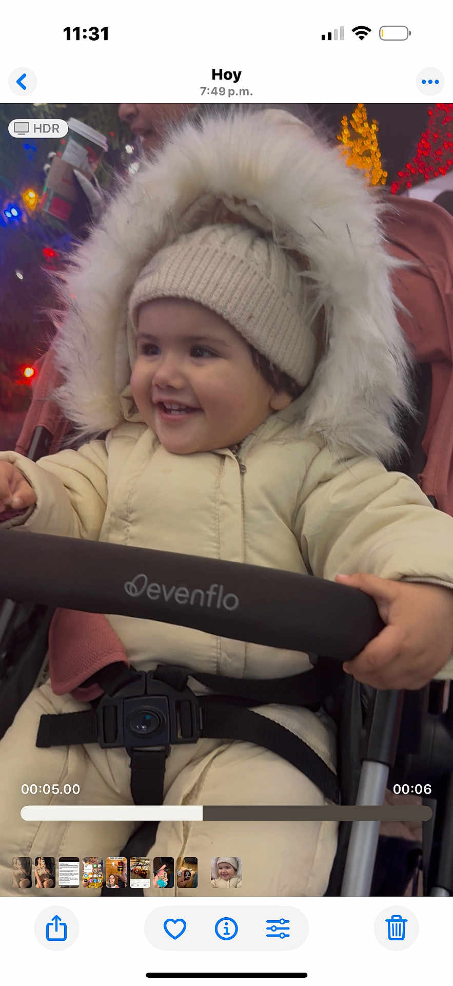 Alaia is registered to the contest to win money with this photo: toddler, child, smiling, winter_clothing, hat, stroller, jacket, baby, happy, outdoor, night, holiday_lights, fur_hood, warm_clothes, person, seatbelt, cute, portrait, festive, seasonal