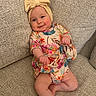 Eleanor joined the competition — help win amazing prizes! baby, child, infant, smiling, portrait, couch, indoor, floral_outfit, headband, bow, colorful_clothing, sitting, relaxed, face, eyes, hands, legs, furniture, home, photography