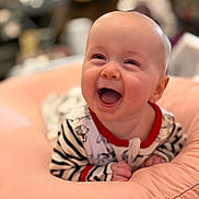 Eleanor is registered to the contest to win money with this photo: baby, infant, child, smiling, laughing, portrait, close_up, indoor, cushion, soft_furnishing, striped_clothing, onesie, red_trim, seated, happy, joyful, face, hands, blurred_background, photography