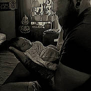 Lillian is registered to the contest to win money with this photo: baby, man, tattoo, sleeping, indoor, window, lamp, pumpkin, jack_o_lantern, halloween, sign, furniture, curtain, shirt, shorts, beard, ear_gauge, person, holding, cozy