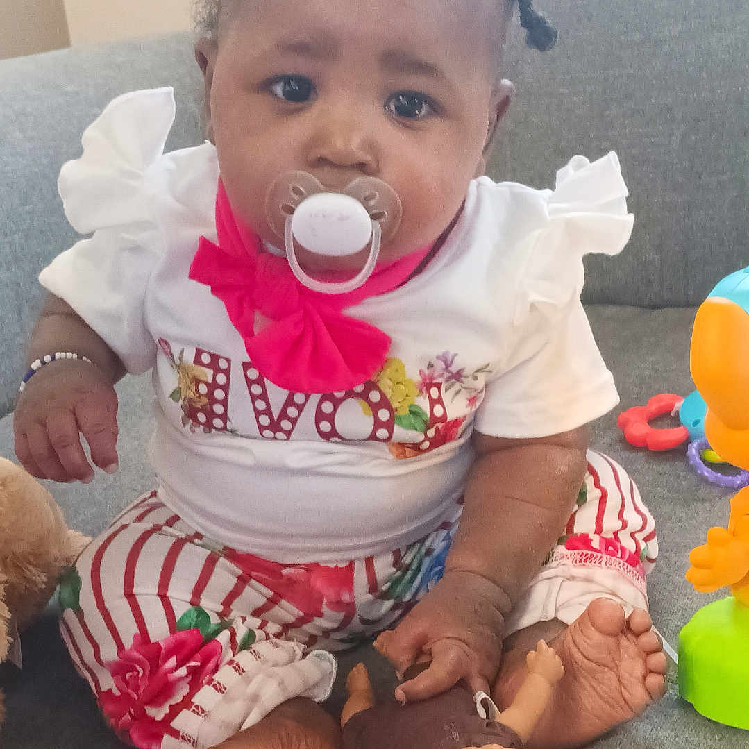 Zoeii Lee joined the competition — help win amazing prizes! baby, child, colorful_clothing, couch, cute, doll, expression, face, foot, hand, indoor, infant, pacifier, pigtails, pink_bow, playtime, sitting, striped_pants, toy, white_shirt