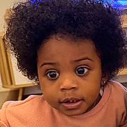 Kaëlyne participe au concours pour gagner de l'argent avec cette photo : afro_hair, blanket, child, couch, cozy, curious, curly_hair, earrings, expression, face, furniture, home, indoor, moon_design, person, sweater, television, toddler, wide_eyes, young_child