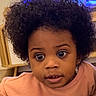afro_hair, blanket, child, couch, cozy, curious, curly_hair, earrings, expression, face, furniture, home, indoor, moon_design, person, sweater, television, toddler, wide_eyes, young_child